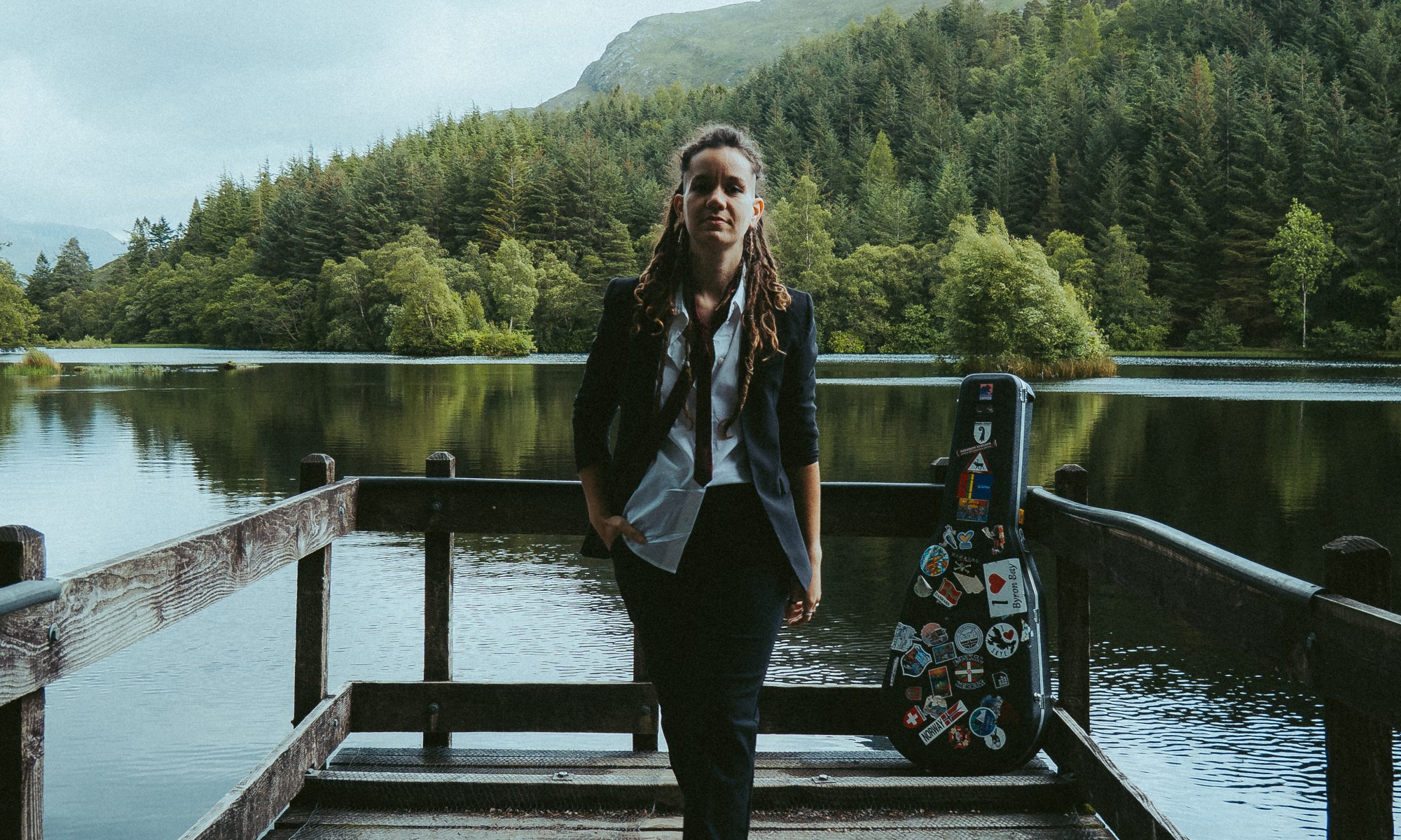 Laura Silverstone on a jetty facing camera with loch and forest behind her
